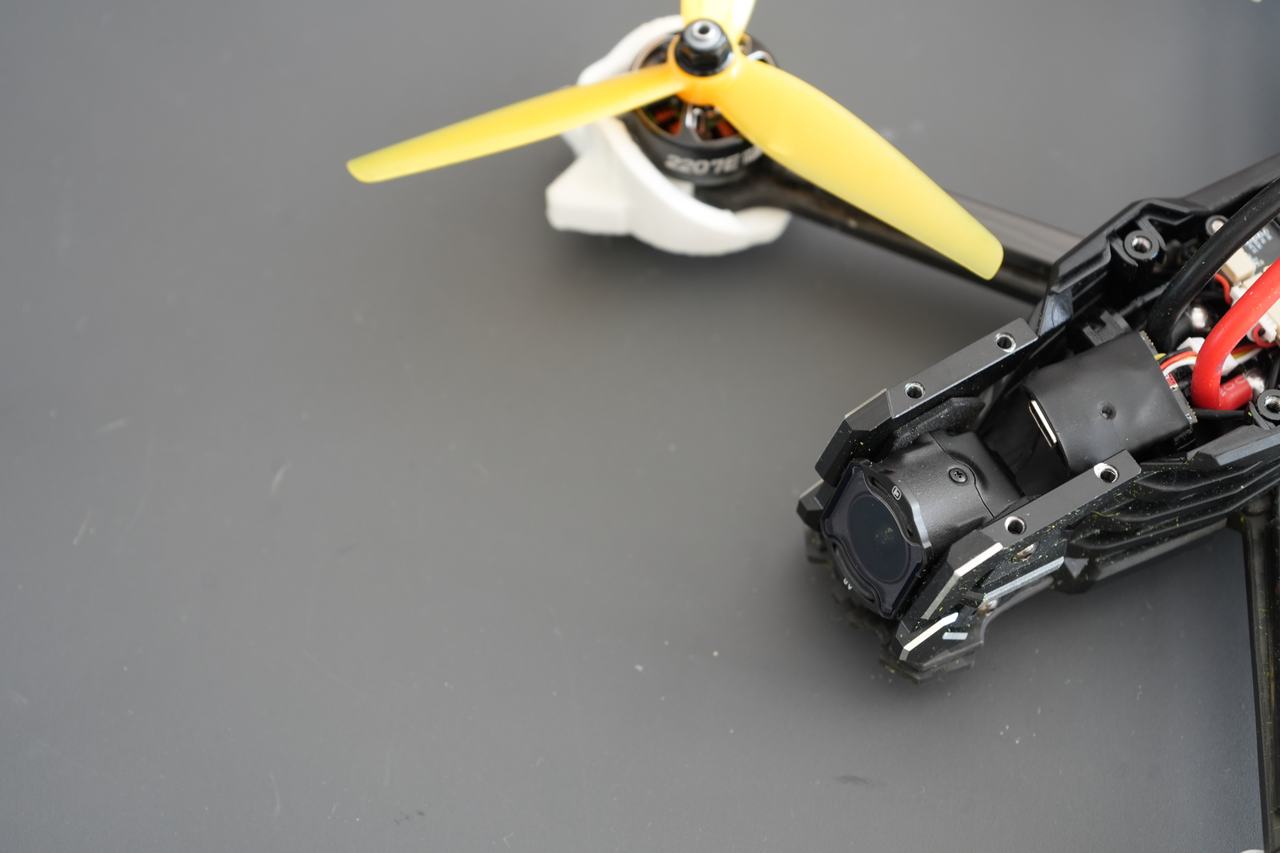 A 5-inch quad on a workbench, The Slate wrapped in black and mounted between the flight controller stack and the camera.
